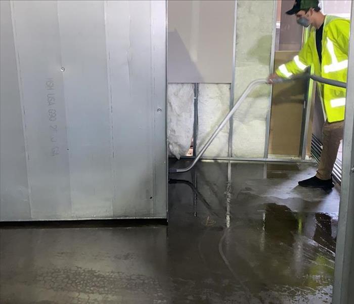 technician sucks up water from concrete warehouse floor
